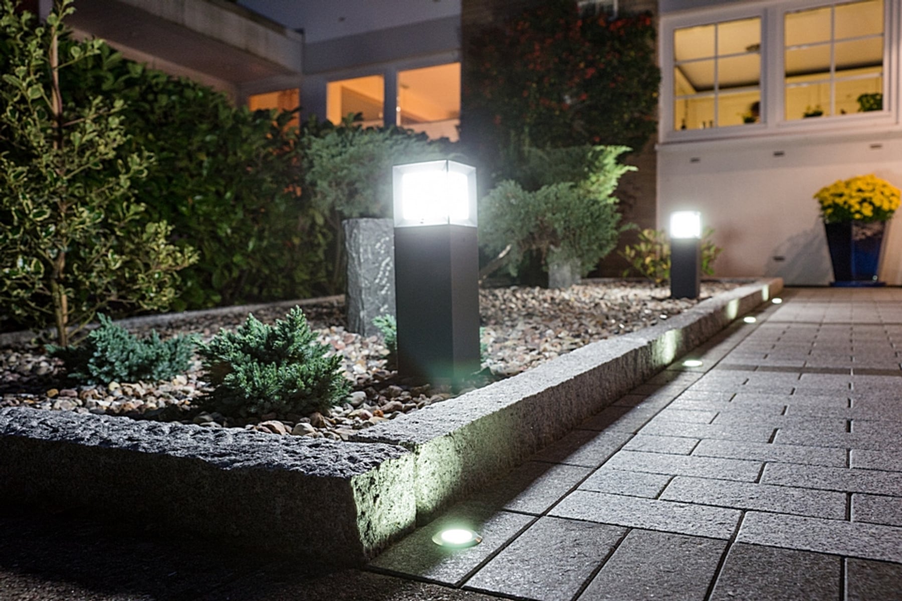 Außenbeleuchtung in Garten bei Nacht mit Haus im Hintergrund